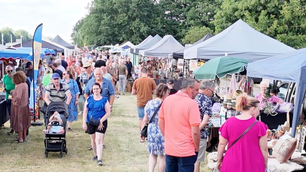 Bezoekers wandelen tussen de kraampjes op de kunst- en ambachtenmarkt in Olmen